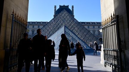 Des passants devant la pyramide du Louvre à Paris, créée par l'architecte Ieoh Ming Pei, le 24 octobre 2023. (MIGUEL MEDINA / AFP)